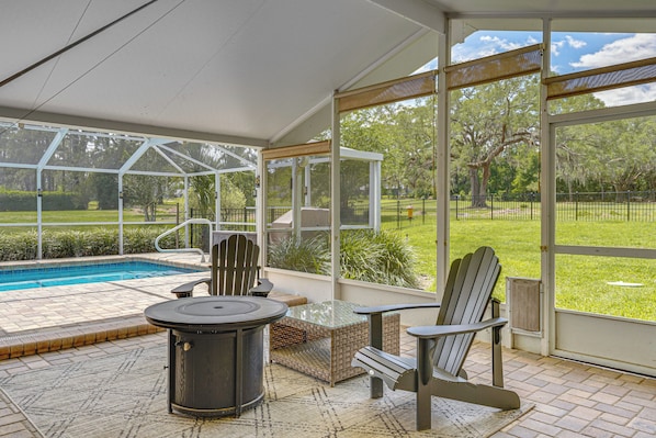 A covered patio with a pool, outdoor furniture, and a view of the yard.