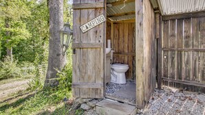 Una estructura de madera rústica con un inodoro y un cartel que indica 'CAMPING'.
