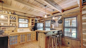 Een rustiek houten interieur van een chalet, met een keuken, een bar en grote ramen.