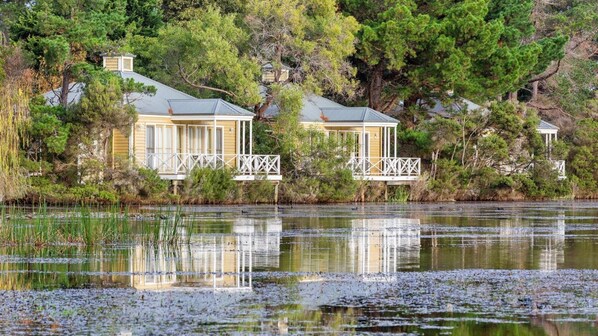A lakeside property with two cabins, each with a balcony and a view of the water.