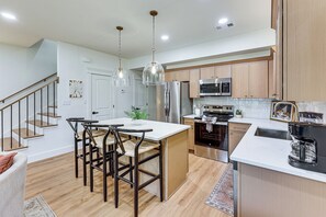 Cocina moderna con una isla central, electrodomésticos de acero inoxidable y una zona de comedor con taburetes de bar.