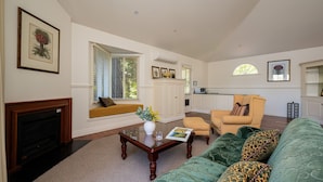 A living room with a fireplace, a sofa, a coffee table, and a window with blinds.