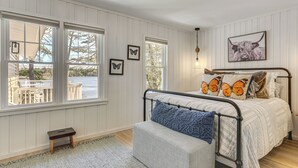 Un dormitorio con cama, un banco y vistas al exterior.