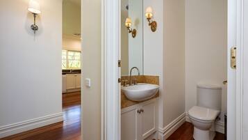 A bathroom with a white sink, a toilet, and wall sconces.