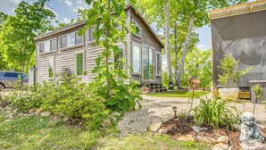 A wooden cabin with a porch, surrounded by greenery and a gravel path. - Tiny Cabin Getaway in the Tennessee River Valley (Rogersville)