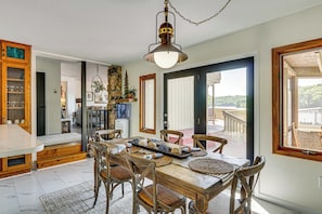 A dining area with a wooden table, chairs, and a hanging light fixture. - Property Windy Cove Waterfront Reserve (Roach)
