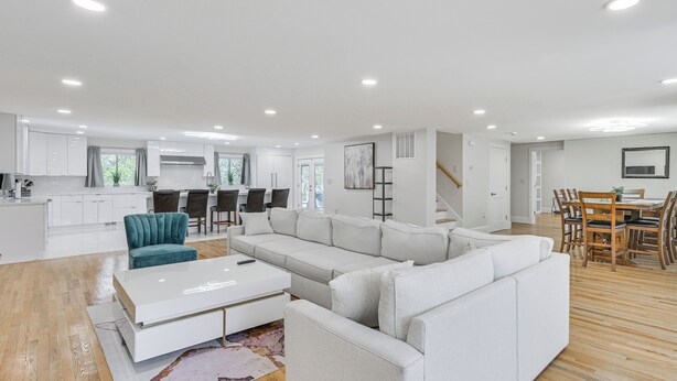 A modern living room with a sectional sofa, a coffee table, and a dining area with wooden chairs and a table. - 2 Mi to Nantasket Beach! Group Retreat w/ Patio (Hull)