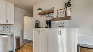 Cocina con armarios blancos, una cafetera y un cartel que dice 'Lake House'.
