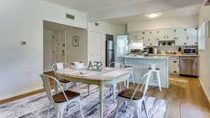 Un espace repas avec une table, des chaises et une cuisine en arrière-plan.