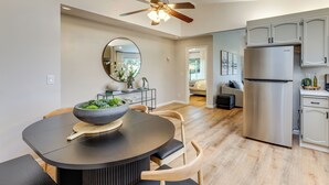 A modern kitchen with a large refrigerator, wooden chairs, a dining table with a bowl of fruit, and a ceiling fan. - Hike, Work & Play! SLO Home: 2 Mi to Beaches (San Luis Obispo)