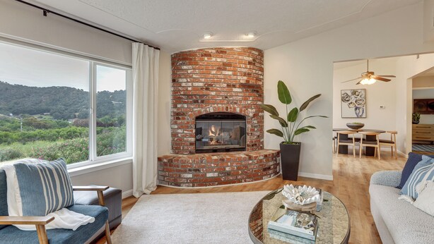 A living room with a brick fireplace, a sofa, a coffee table, and a view of the outdoors. - Hike, Work & Play! SLO Home: 2 Mi to Beaches (San Luis Obispo)