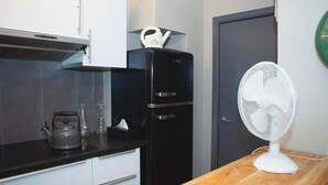 A compact kitchen with a black refrigerator, a white fan, and a kettle on the counter. - Holiday stay in center of Verviers (Verviers)