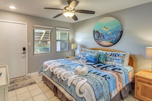 A bedroom with a bed, a ceiling fan, a painting, and a window. - Boardwalk to Port Aransas Beach! Condo w/ Pool (Port Aransas)