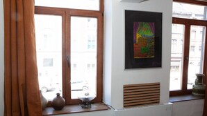 Et værelse med et stort vindue, en radiator og en vase på vindueskarmen.