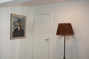 A white door, a framed painting, and a floor lamp.