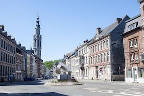 Una calle con edificios históricos, una glorieta y una alta aguja de iglesia.