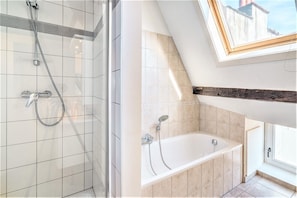 Een badkamer met een douche, bad en dakraam.
