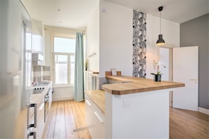 Een moderne keuken met een centraal eiland, een eetruimte met uitzicht en een woonruimte met een groot raam.