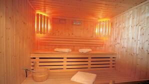 Una sauna amb parets de fusta, una panxa, un cubell i tovalloles.