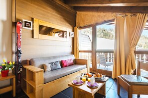Interior acolhedor de uma cabana com um sofá de madeira, uma mesa de jantar com café da manhã e um suporte para esquis.