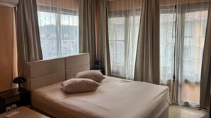 A hotel room with a bed, a nightstand, a lamp, and a window with curtains. - Large Double Room in Hotel Darling Bankya (Bankya)
