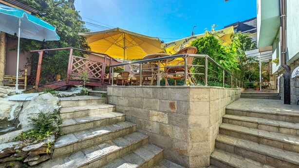Outdoor stone steps leading to a seating area with yellow umbrellas and wicker furniture. - Large Double Room in Hotel Darling Bankya (Bankya)