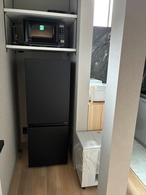 Une petite cuisine équipée d’un four à micro-ondes, d’un réfrigérateur et d’un petit plan de travail.