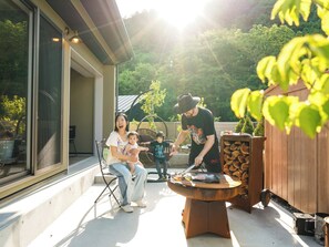 An outdoor patio with a grill, a dining table, and a seating area with chairs.