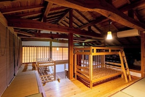 Quarto em estilo japonês tradicional com tatames, uma cama beliche de madeira e uma porta corrediça com painéis shoji.