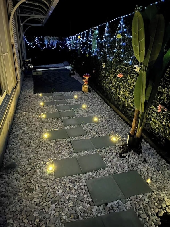 Un sentier agrémenté de pas japonais, de luminaires décoratifs et d’une petite structure illuminée.