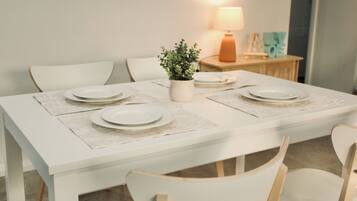 A dining table with white placemats, a potted plant, and a lamp on a wooden side table.