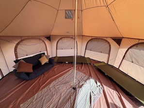 A tent with a central pole, a sofa with cushions, and a sleeping area.