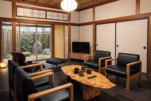 A traditional Japanese-style room with tatami flooring, a low wooden table, black leather chairs, a television, and sliding doors. - Room A Up to 4 adults  2 preschool children / Izumo City Shimane (Izumo City)
