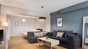 Ein modernes Wohnzimmer mit einer Couch, einem Couchtisch, einem Fernseher und Kunstwerken an den Wänden.