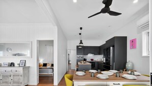 A modern kitchen with dark cabinets, a central island, and a dining area with yellow chairs.