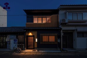 A two-story building with a dark facade, a visible entrance with a metal gate, and a bicycle parked outside. - Hanaikada House 8minute walk from Kyoto Station / Kyoto City Kyōto (Kyoto City)