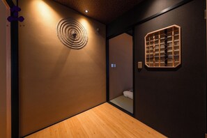 A hallway with a wooden floor, a circular wall decoration, and a geometric wall panel. - Hanaikada House 8minute walk from Kyoto Station / Kyoto City Kyōto (Kyoto City)