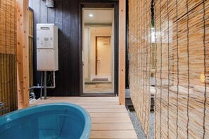 Un intérieur en bois avec une baignoire bleue, un appareil électroménager blanc et un mur en bambou.