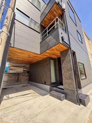Un edificio moderno a più piani con una terrazza in legno, un garage e un piccolo spazio esterno.