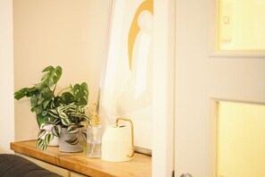 En træhylde med potteplanter, en glasflaske og en hvid genstand.