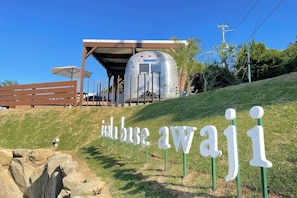 A modern building with a covered entrance, a sign reading 'inbase awayi,' and a parked trailer.