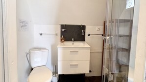 Un baño con inodoro, lavabo y cabina de ducha de cristal.