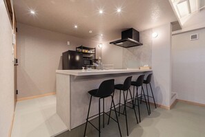 A compact kitchen with a bar area, a microwave, and a black range hood. - Fully renovated in 2025 Entire building for rent / Edogawa Ward Tokyo (Edogawa Ward)