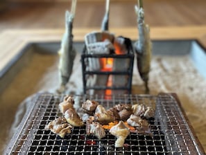 Uma churrasqueira com espetos de carne e brasa.