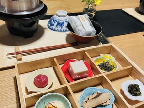 A wooden tray with compartments containing various food items, a pair of chopsticks, a teapot, and a small vase with flowers. - Entire building rental Inn with openair bath un / Yoshino District Nara (Yoshino District)