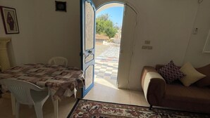 Ein Zimmer mit einem Bett, einem Tisch mit Stühlen, einer Couch und einer offenen Tür zu einem Außenbereich.