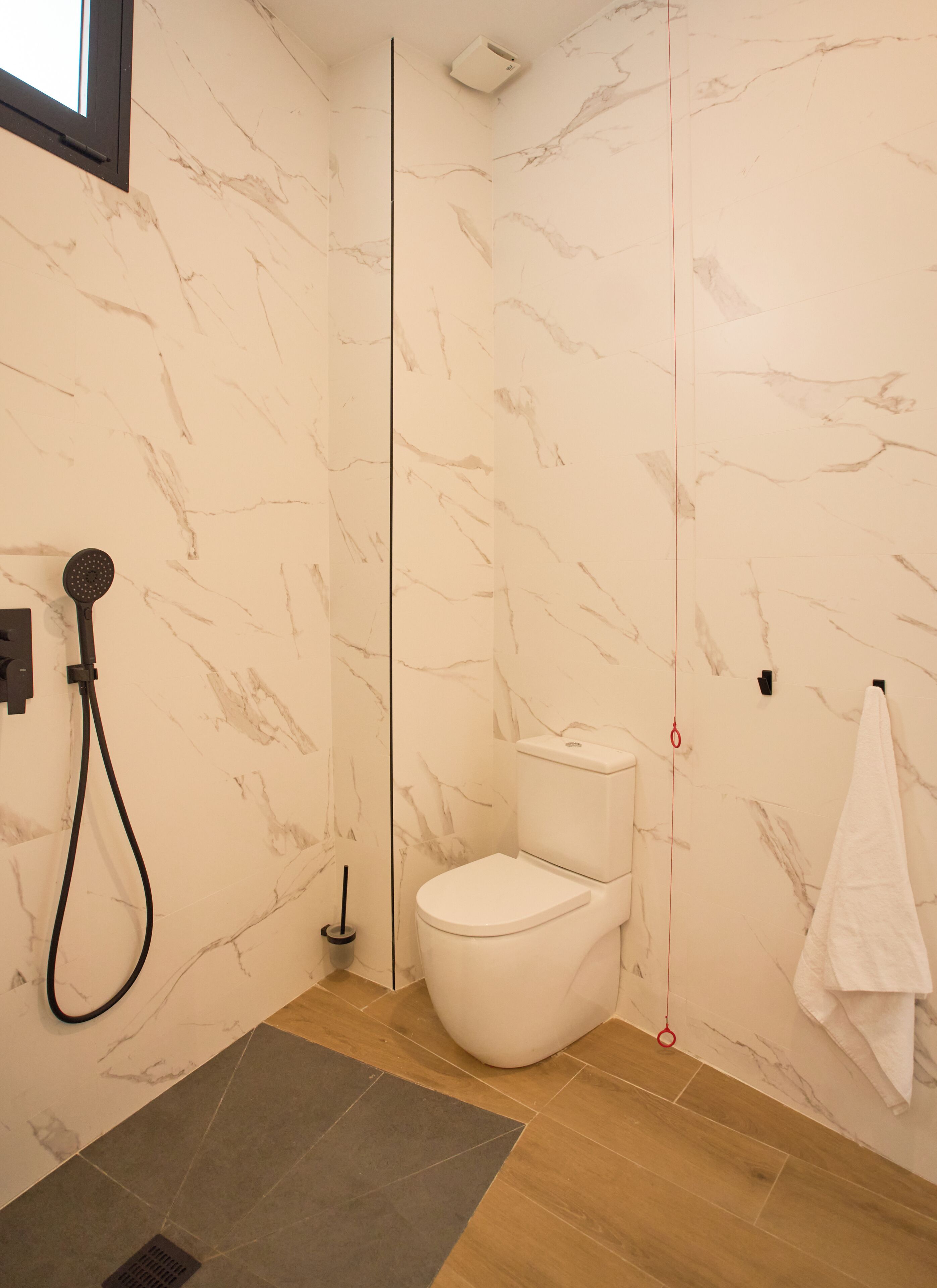 Un baño moderno con ducha, inodoro y toallero.
