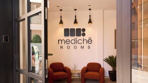 A modern interior with a reception area, two sofas, and a sign reading 'mediché rooms'.
