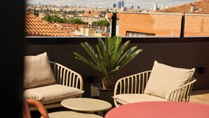 A balcony with two white wicker chairs, a small round table, and a potted plant.