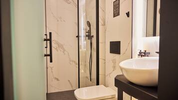 Deluxe studio | Badkamer | Een douche, een haardroger, handdoeken, zeep